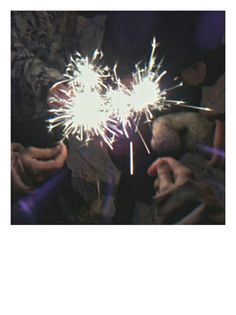 two people holding sparklers in their hands and one person is holding something with the other hand