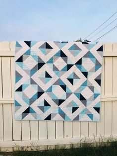 a blue and white quilt hanging on a fence