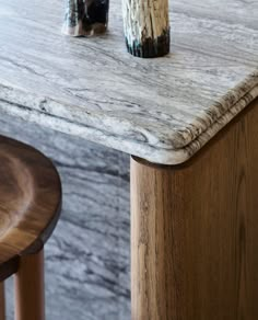 two vases sitting on top of a marble table next to a wooden bar stool