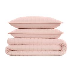 three pillows stacked on top of each other in different colors and sizes, one pink