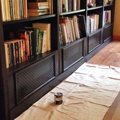 the bookshelves are full of books and there is a can of paint on the floor