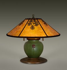 a lamp that is sitting on top of a wooden base with a leaf design shade