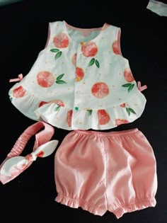 the doll is wearing pink shorts and a white top with oranges on it's sleeves