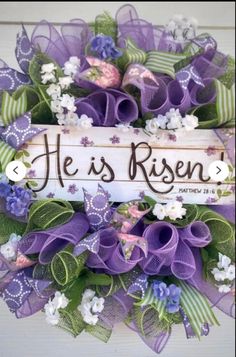 a wreath with purple and white flowers on it that says he is risen, painted in wood