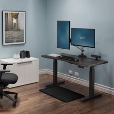 a computer desk with two monitors and a printer on it in an office space that has hard wood flooring