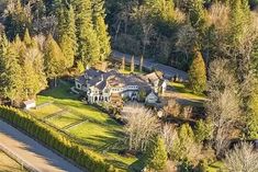 an aerial view of a large home surrounded by trees and grass in the middle of a wooded area