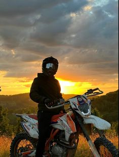 a person on a dirt bike with the sun setting in the back ground behind them