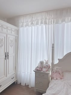 a bedroom with white furniture and curtains on the windowsill