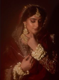 a woman in a red and gold bridal outfit with her hands on her chest