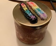 there are three crocheted hair clips on top of a tin canister that is sitting on the table