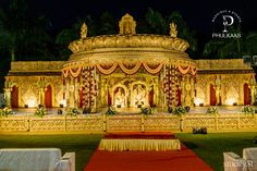 an elaborately decorated stage in the middle of a lawn with white and gold decorations