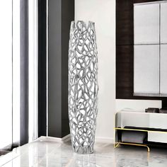 a tall white vase sitting on top of a marble floor next to a mirror and cabinet