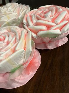 three pink flowers sitting on top of a wooden table