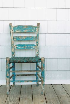 an old blue chair sitting on top of a wooden floor next to a white brick wall