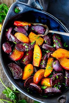 roasted beets and carrots in a pan with a serving utensil on the side