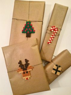 four christmas presents wrapped in brown paper and decorated with bead designs, including a cross - stitch tree