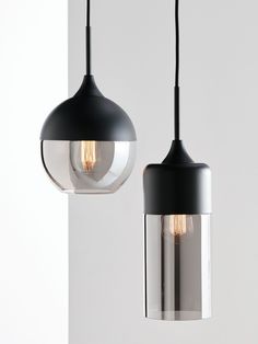 two black and clear glass pendant lights hanging from a ceiling fixture in a white room