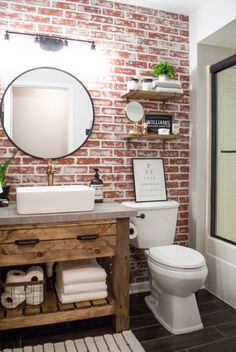 a white toilet sitting next to a bathroom sink under a mirror on top of a wooden cabinet