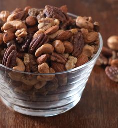 a glass bowl filled with nuts on top of a wooden table