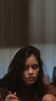 a young woman sitting on top of a bed holding a remote control in her hand