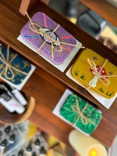 three square coasters tied with twine on top of a wooden table next to candles