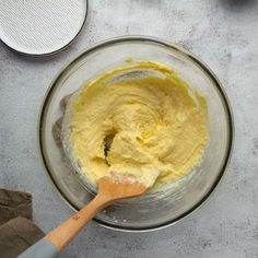 a bowl filled with yellow batter next to a spatula on top of a counter