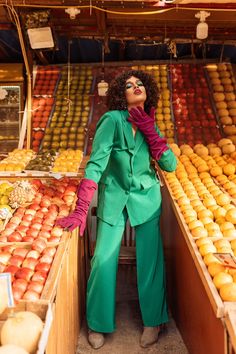 a woman standing in front of an assortment of fruits