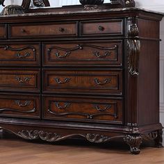 an ornately carved wooden dresser with mirror on top