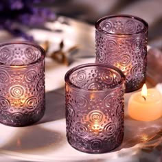 three purple glass candles sitting on top of a table