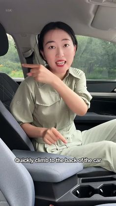 a woman sitting in the back seat of a car pointing at something