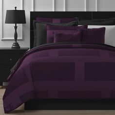 a bed room with a neatly made bed and purple comforter