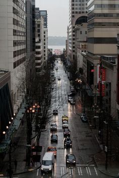 a city street with cars driving down it and buildings on both sides in the background