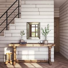 a wooden table sitting under a window next to a stair case with potted plants on it