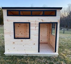 a small house made out of wood with windows on the side and two doors open