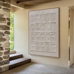 a large white wall hanging on the side of a stone building next to a wooden bench