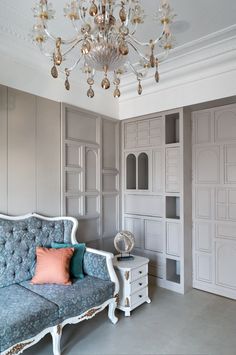 a living room filled with furniture and a fancy chandelier above it's headboard