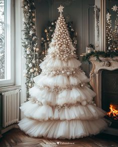 a white christmas tree in front of a fireplace