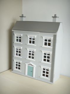 a white doll house sitting on top of a table next to a window and door