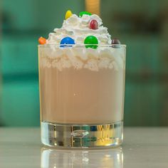 a dessert with white frosting, candy and cream in a glass on a table