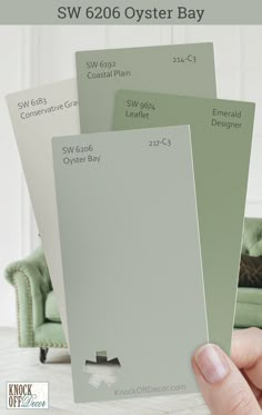 a hand holding three different shades of paint for the sw 606 oyster bay color scheme