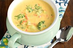 a bowl of soup with broccoli and carrots in it on a table