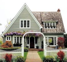 a house with a white picket fence in front of it and flowers on the side