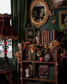 a bookshelf filled with lots of books next to a lamp and pictures on the wall