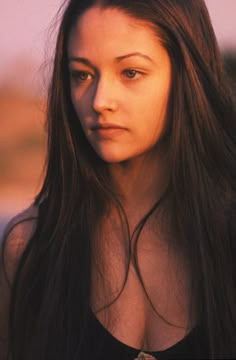 a woman with long brown hair is looking at the camera