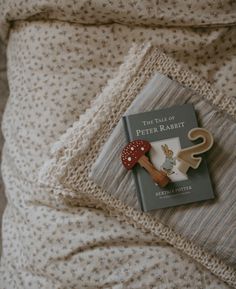 there is a book on the bed next to some scissors and a mushroom brooch