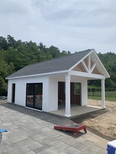 a small white building with a red bench in front of it on a patio area