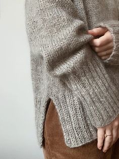 a close up of a person wearing a sweater and holding their hands in their pockets