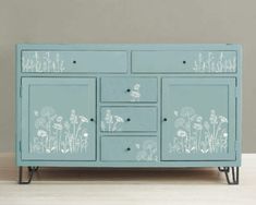 a blue dresser with white flowers painted on it