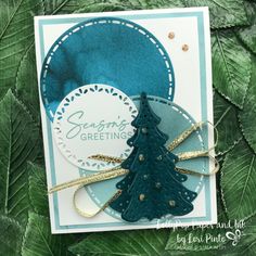 a close up of a card with a christmas tree on it and green leaves in the background