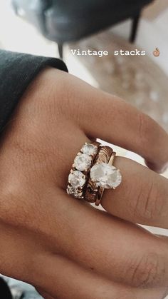 a woman's hand wearing a ring with three stones on it and the middle finger